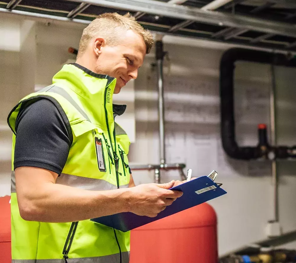 Huoltomies tekee merkintöjä taloyhtiön lämmönsäätöön liittyen.